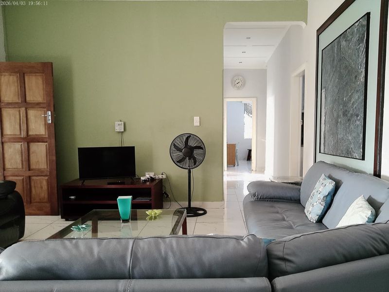 A living room featuring tiled flooring and an archway leading to a hallway, with neutral wall tones and recessed lighting.