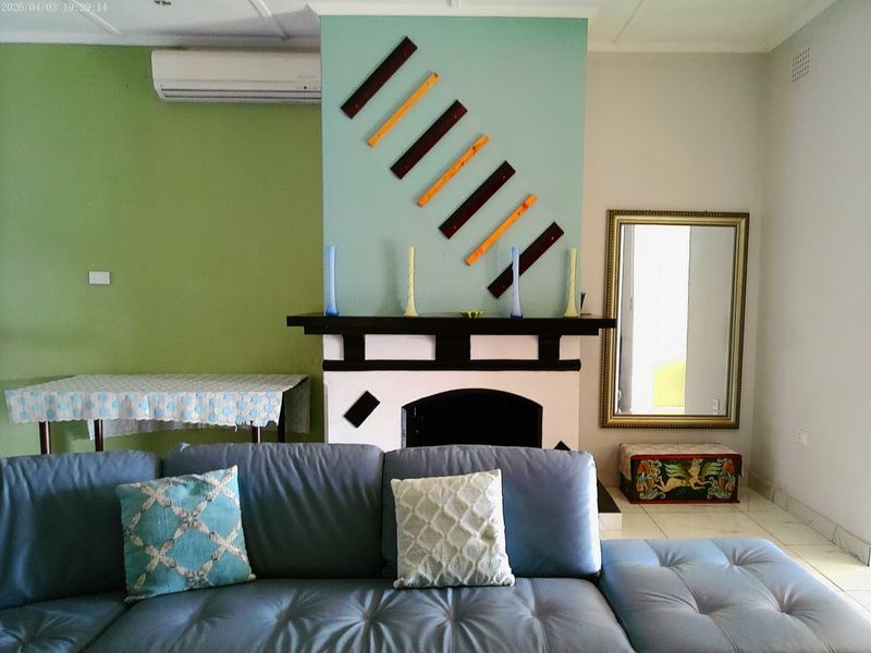 Living room featuring a central fireplace with a mantelpiece, tiled flooring, and a wall-mounted split-system air conditioning unit.