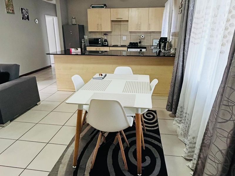 Open-plan living and dining area featuring ceramic tiled flooring and a functional kitchen with granite countertops and built-in cabinetry.