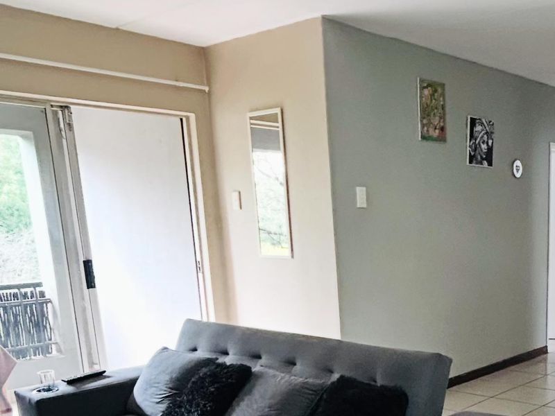 A living room featuring tiled flooring and a sliding glass door providing access to an outdoor area.