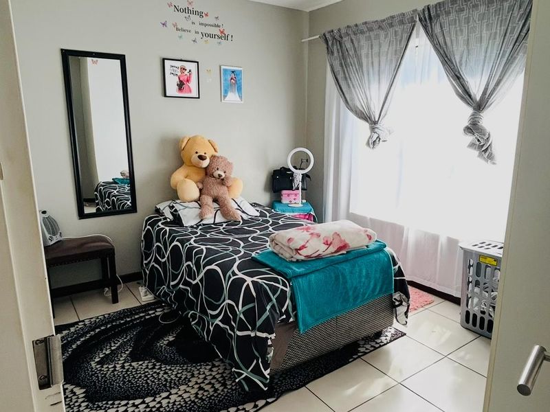 A functional bedroom featuring tiled flooring and natural light through a window with installed curtain rods.