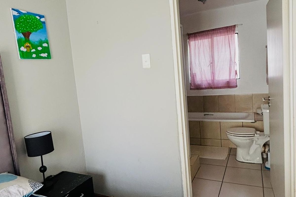 A bedroom featuring tiled flooring and direct access to an en-suite bathroom equipped with a bathtub and toilet.