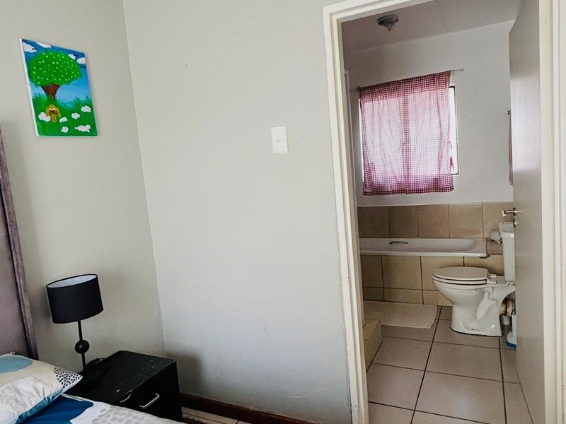 A bedroom featuring tiled flooring and direct access to an en-suite bathroom equipped with a bathtub and toilet.