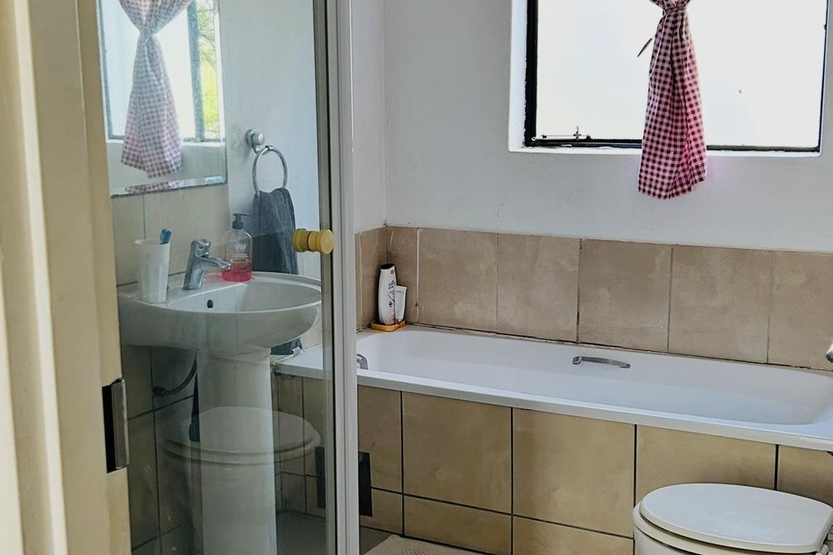 A functional bathroom featuring a pedestal basin, a separate shower enclosure, a bathtub, and a toilet with neutral floor and wall tiling.