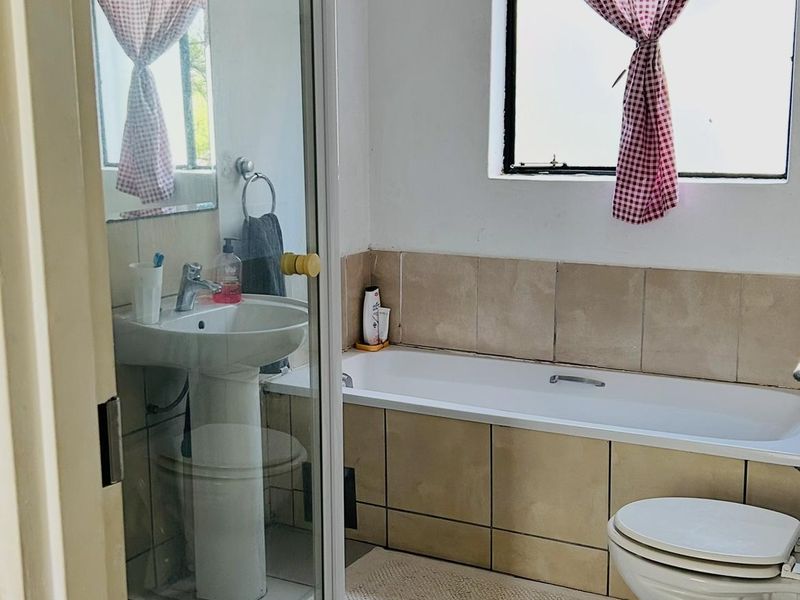 A functional bathroom featuring a pedestal basin, a separate shower enclosure, a bathtub, and a toilet with neutral floor and wall tiling.