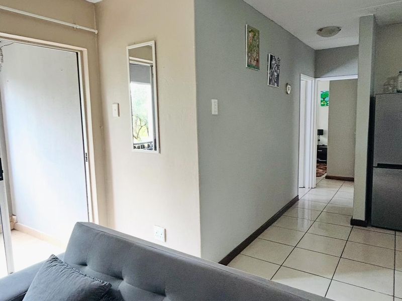 Open plan living area featuring tiled flooring, neutral wall tones, and a sliding glass door leading to an outdoor space.