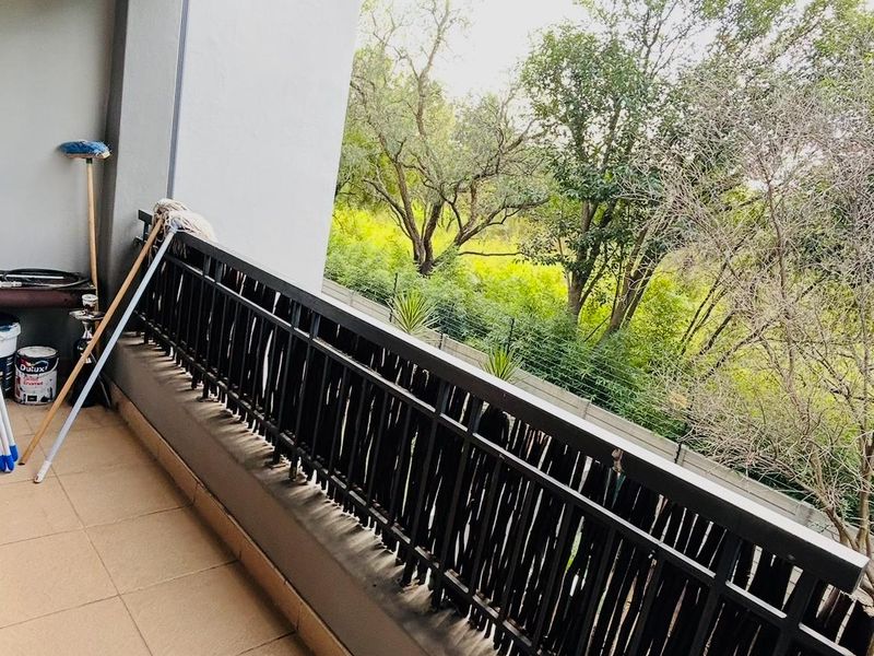 A covered balcony featuring tiled flooring and a decorative privacy screen, offering a pleasant view of the surrounding trees.