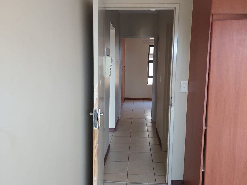A functional hallway featuring tiled flooring, built-in storage cupboards, and an intercom system, providing access to the rest of the apartment.