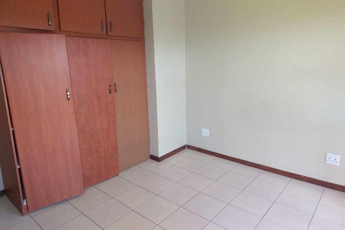 An empty bedroom featuring tiled flooring and built-in wooden cupboards, providing a neutral canvas for personalization.