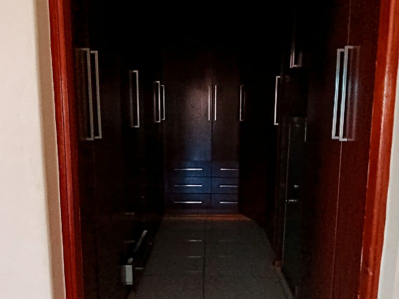 A walk-in closet area featuring dark wood built-in cupboards and tiled flooring, providing ample storage space.