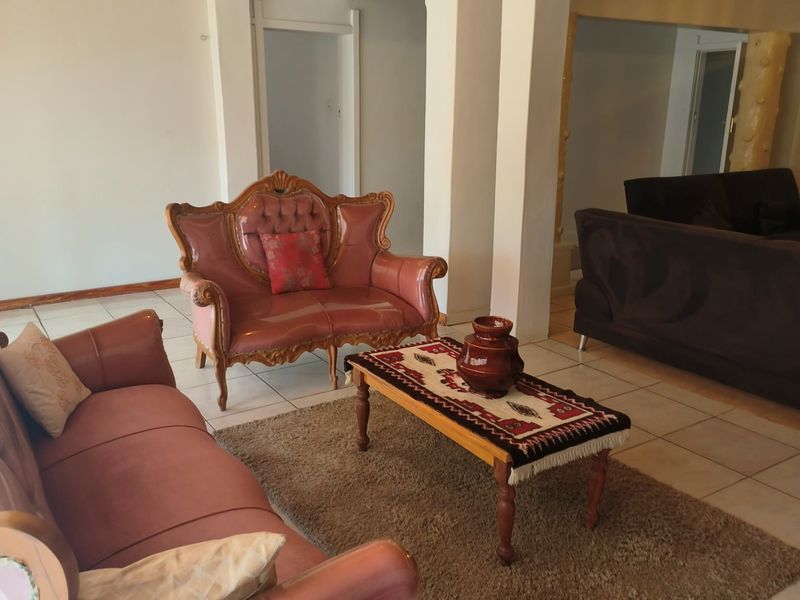 Spacious living area featuring tiled flooring and structural columns, offering an open-plan layout suitable for various furniture arrangements.
