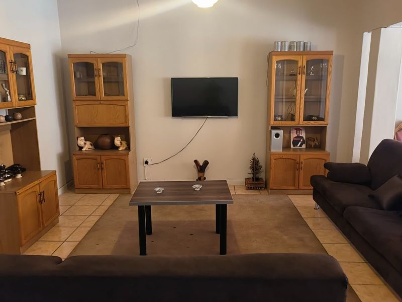 A living room featuring tiled flooring and a neutral wall finish, providing a functional space for relaxation and entertainment.