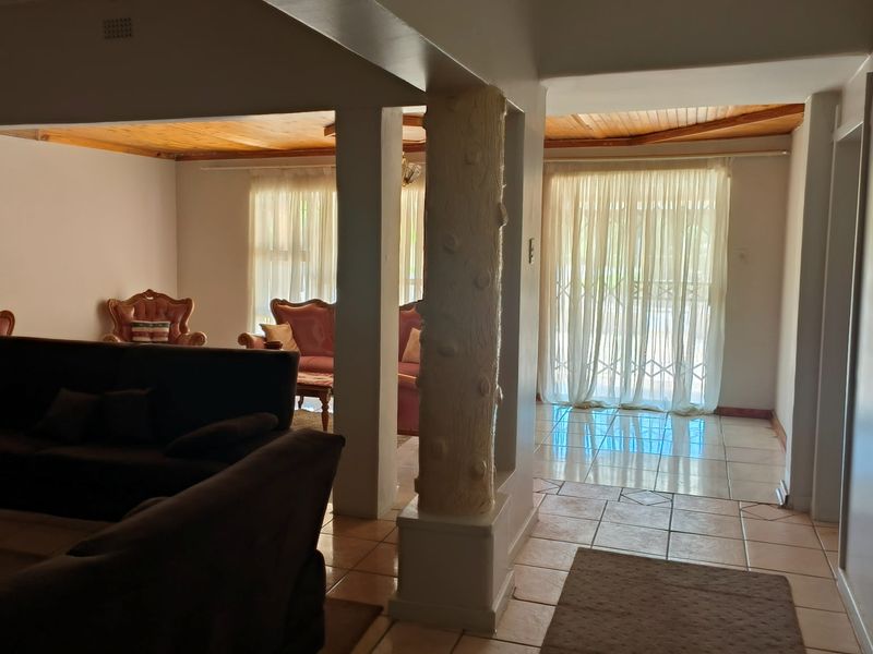 Spacious open-plan living area featuring tiled flooring, a timber-clad ceiling, and a unique decorative pillar, offering a versatile layout for family living.
