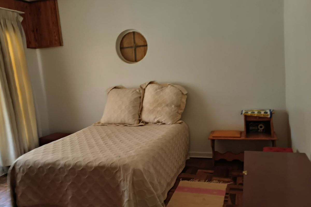 A bedroom featuring classic parquet flooring and a distinctive circular window, offering a neutral canvas for potential interior updates.
