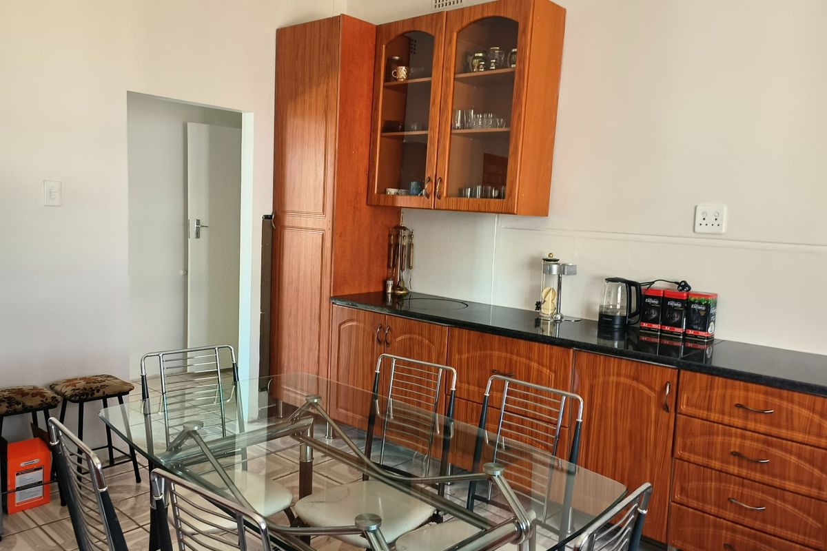 A functional kitchen area featuring wood-finish cabinetry, dark granite countertops, and tiled flooring, providing a practical workspace for daily meal preparation.