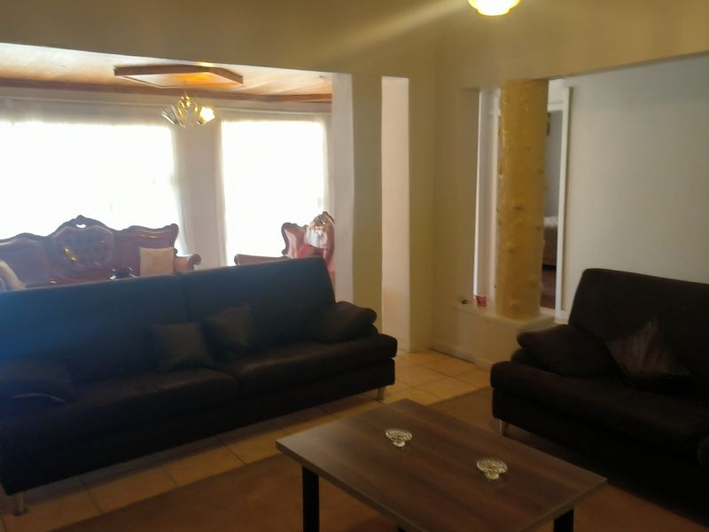 Spacious living area featuring tiled flooring, a decorative column, and recessed ceiling details, offering a versatile layout for comfortable family living.