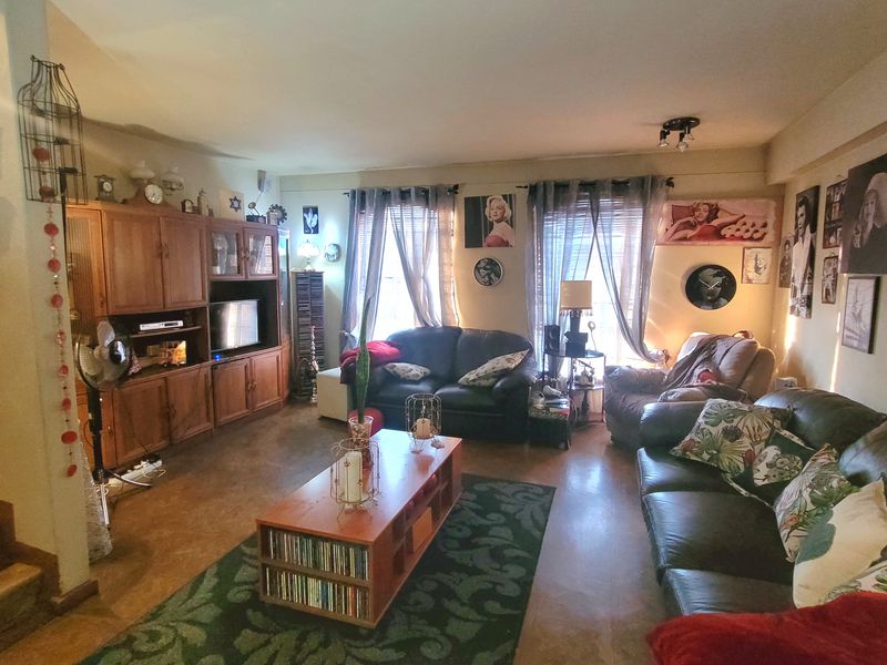 A spacious living room featuring built-in wooden cabinetry and laminate flooring, offering a comfortable and functional layout for relaxation.