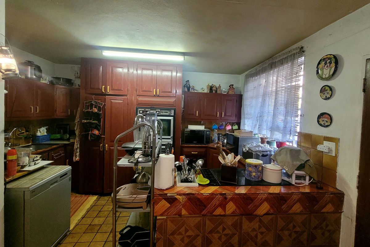 A dated kitchen featuring dark wood cabinetry, tiled countertops, and a built-in oven, offering significant potential for a modern renovation.
