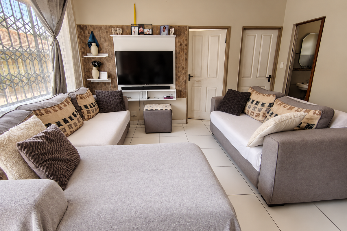 A well-maintained living room featuring tiled flooring, a built-in media unit, and direct access to adjacent rooms.