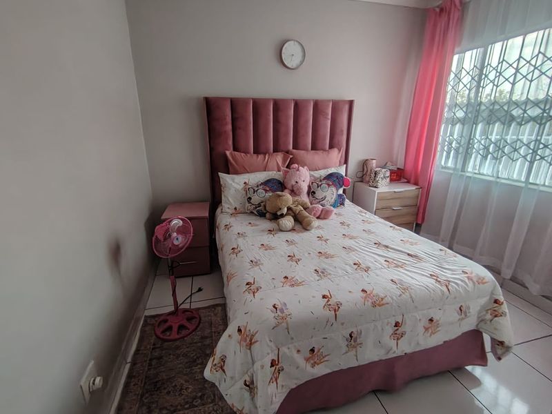 A bedroom featuring tiled flooring and a security gate on the window, with visible wall staining requiring attention.