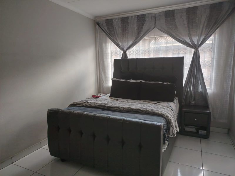 A bedroom featuring tiled flooring and a window fitted with a security gate.