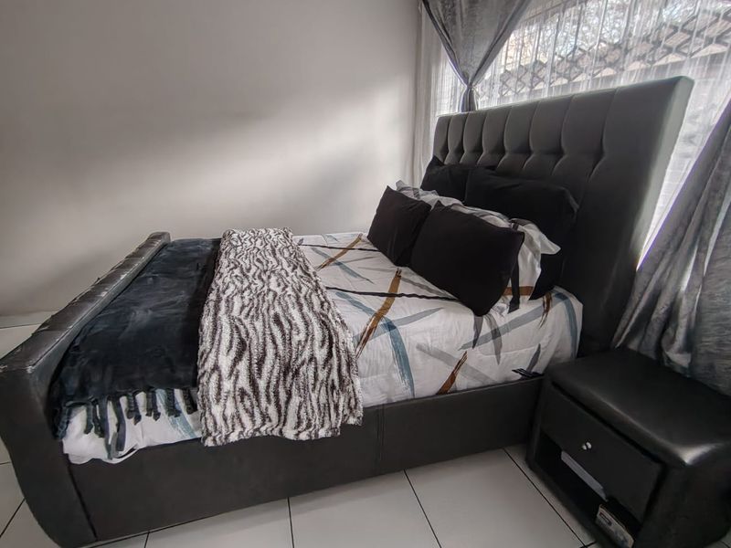 A bedroom featuring tiled flooring and window treatments, providing a functional space for rest.