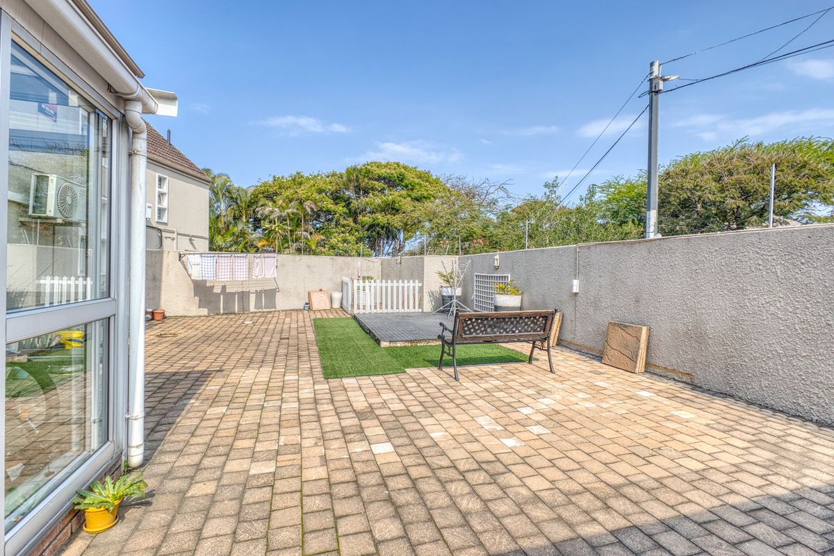 A paved rear courtyard area featuring a boundary wall and direct access to the main dwelling.