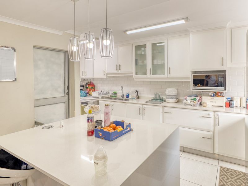 Modern kitchen featuring a central island with quartz countertops, white shaker cabinetry, subway tile backsplash, and integrated microwave, offering a clean and functional workspace.
