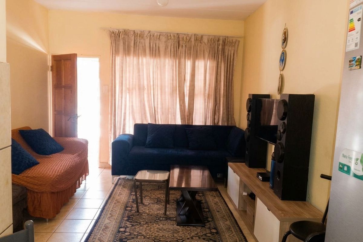 A living room area featuring tiled flooring and direct access to an exterior space through a timber door.