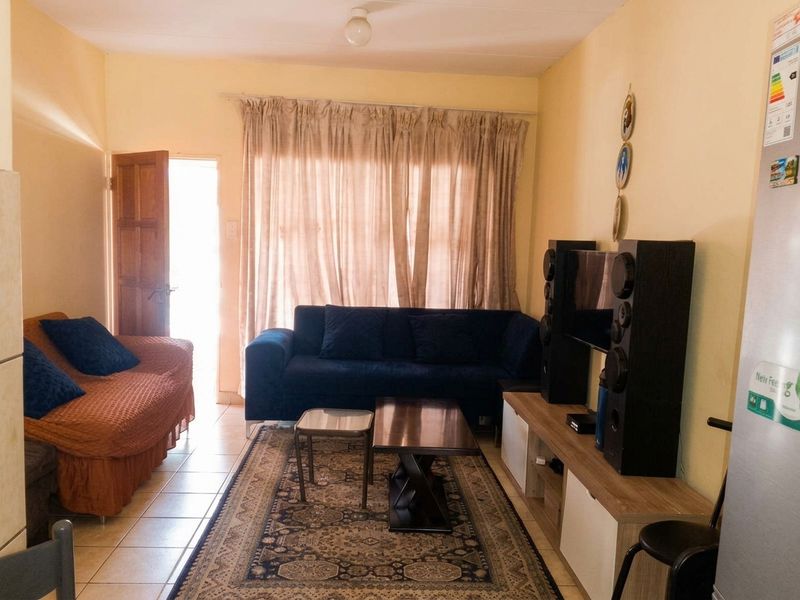 A living room area featuring tiled flooring and direct access to an exterior space through a timber door.