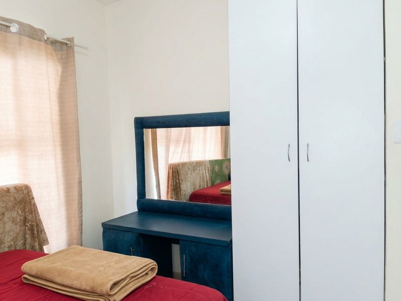 A bedroom featuring a white built-in wardrobe and a window with neutral curtains.