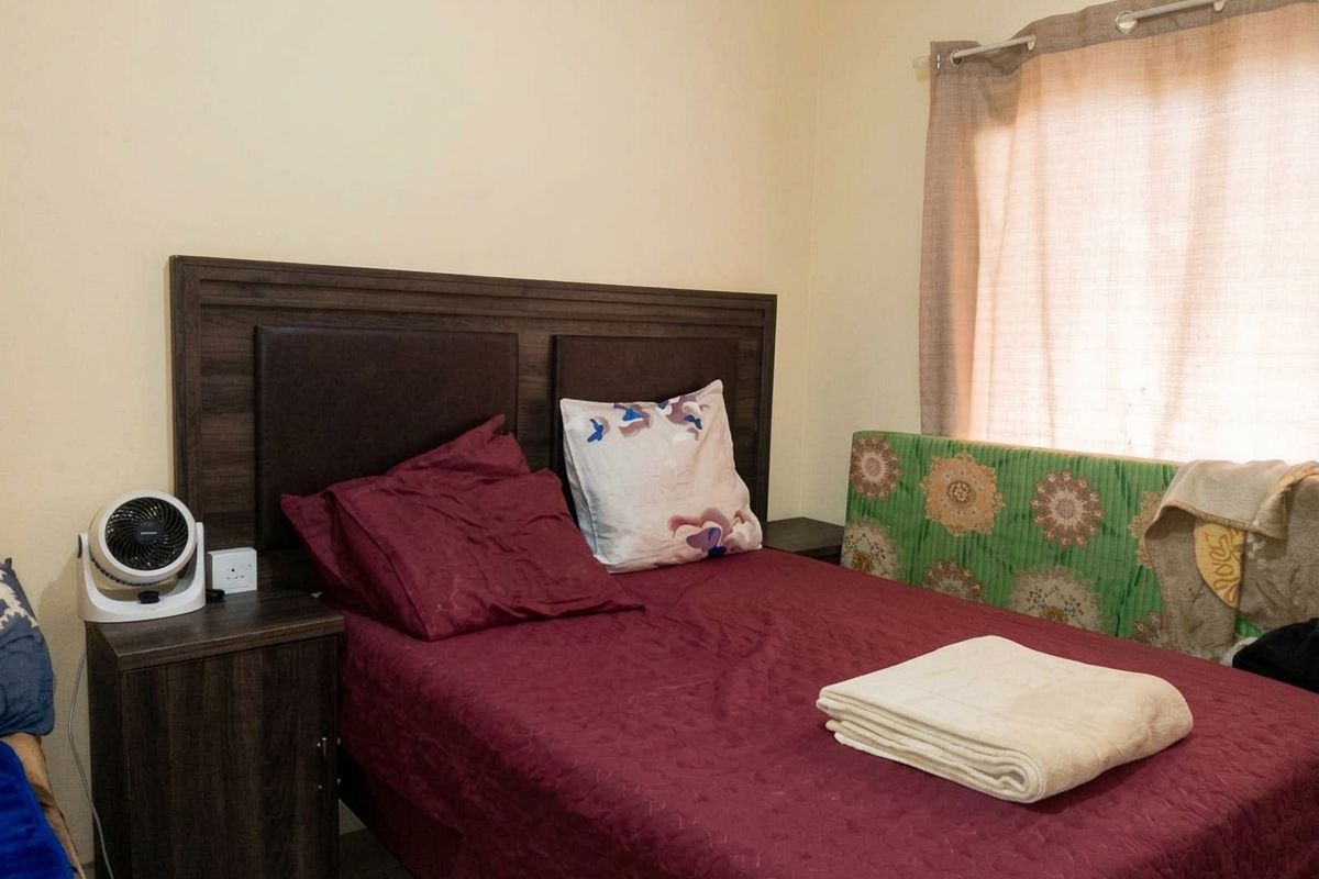 A standard bedroom featuring a window with a curtain rail and neutral wall finishes.