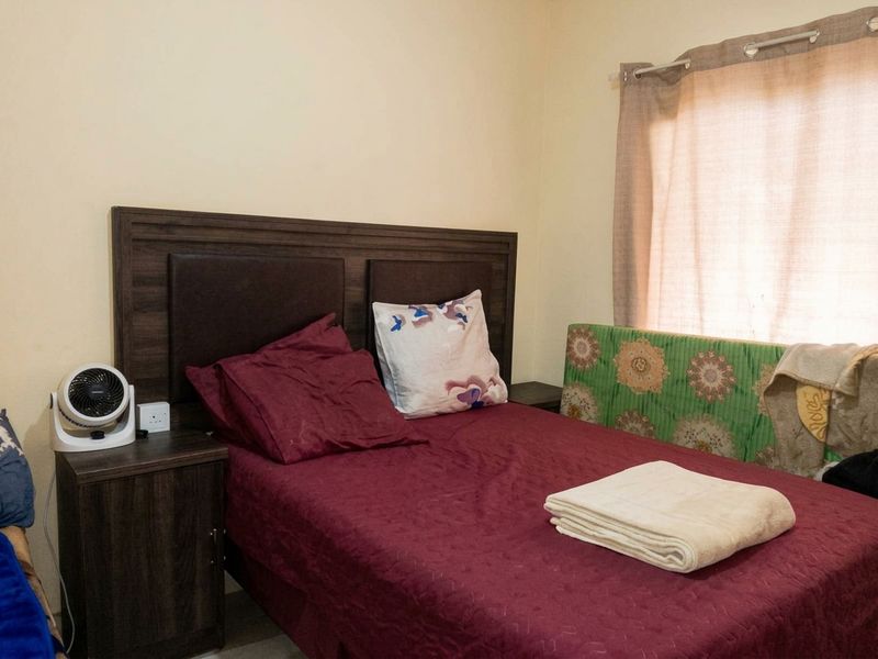 A standard bedroom featuring a window with a curtain rail and neutral wall finishes.