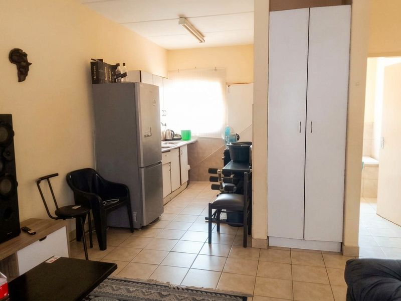 A functional kitchen area featuring tiled flooring, built-in cabinetry, and a tall storage cupboard, providing essential utility space within the apartment.