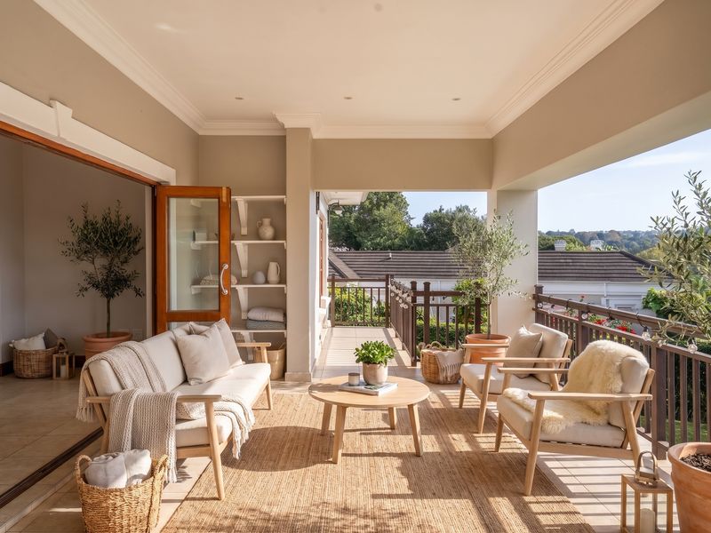 A spacious covered balcony featuring tiled flooring, built-in shelving, and seamless access to the interior through large sliding glass doors.