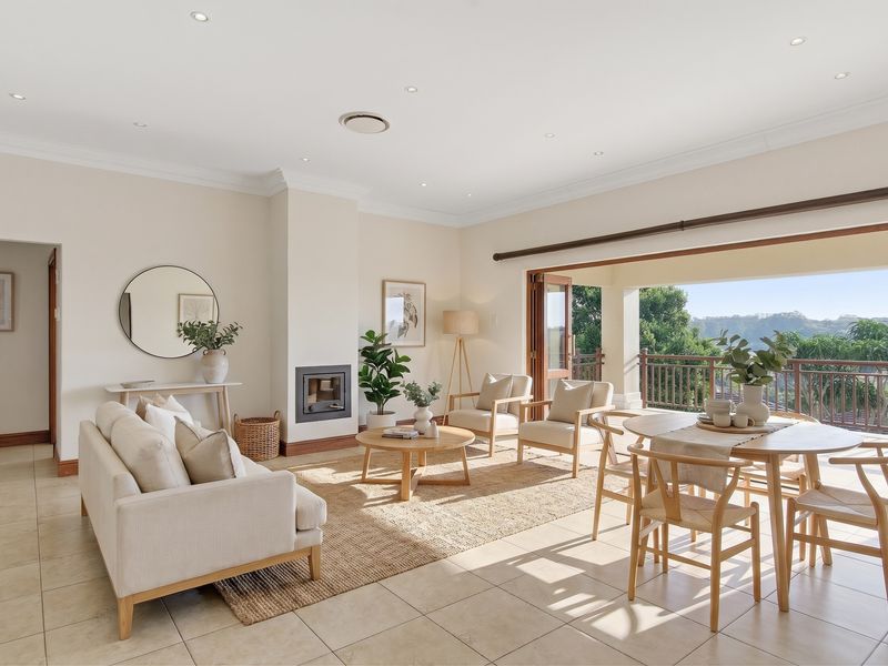 Spacious open-plan living and dining area featuring tiled floors, a built-in fireplace, and seamless access to a balcony with scenic views.