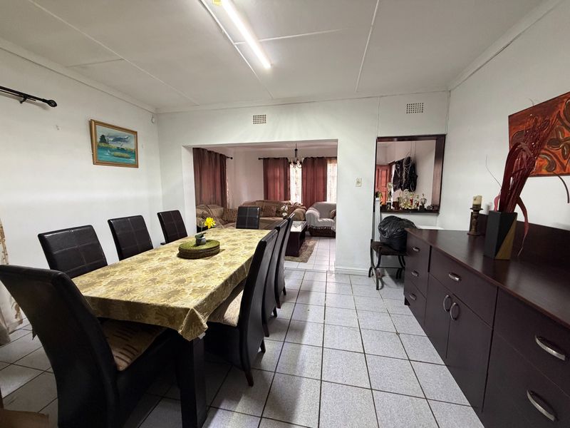 Open plan dining and living area featuring tiled flooring and a built-in serving counter, offering a functional layout for family gatherings.