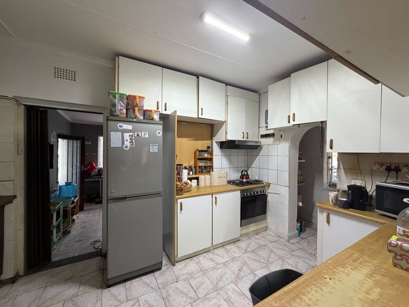 A functional kitchen featuring built-in cabinetry, a tiled backsplash, and integrated cooking appliances, offering potential for modernization and aesthetic updates.