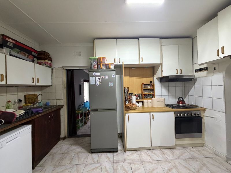 A functional kitchen featuring built-in cabinetry, a tiled backsplash, and integrated cooking appliances, offering potential for a modern cosmetic update.