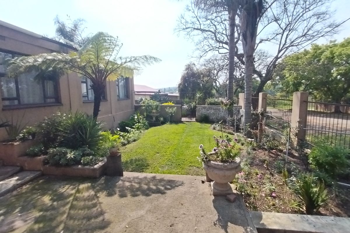 A rear garden area featuring a concrete patio, established lawn, and perimeter fencing, providing a private outdoor space adjacent to the main dwelling.