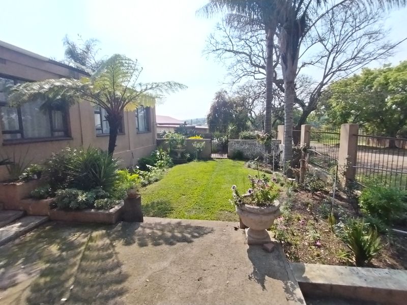 A rear garden area featuring a concrete patio, established lawn, and perimeter fencing, providing a private outdoor space adjacent to the main dwelling.