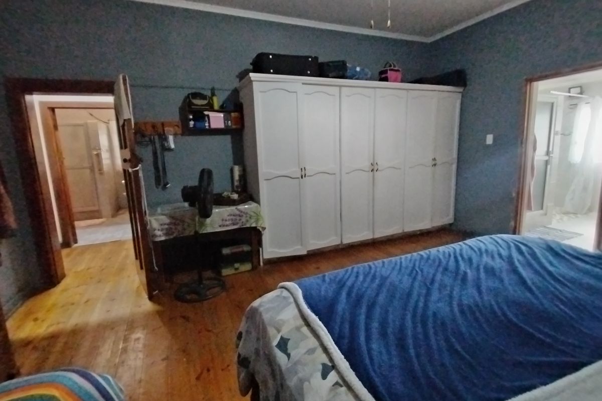 A bedroom featuring hardwood flooring, a large built-in wardrobe, and access to adjacent rooms.