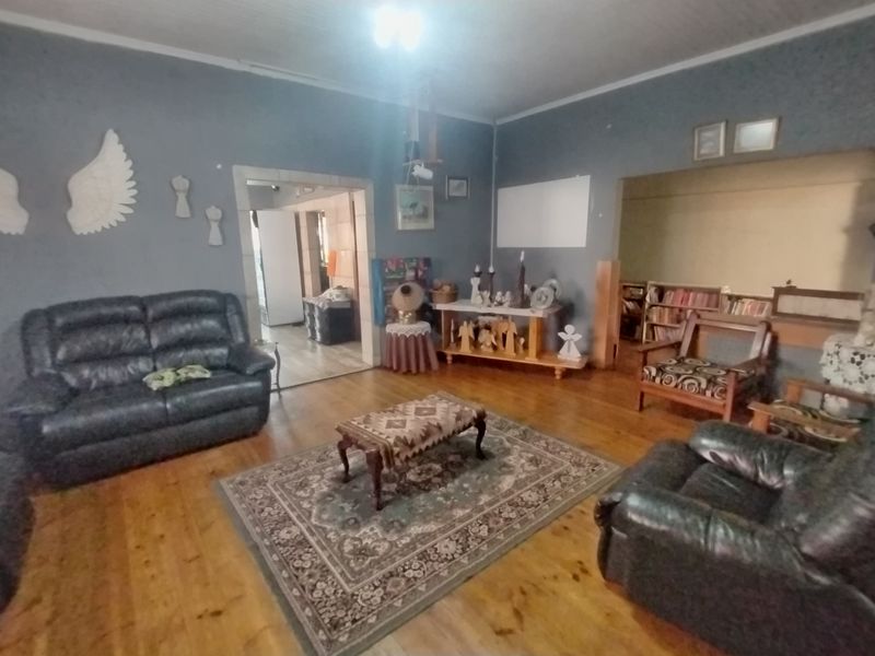 Spacious living room featuring original hardwood flooring and timber ceilings, with an open archway leading to adjacent living areas.