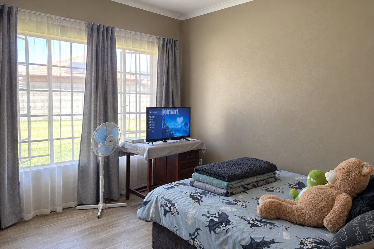 A bedroom featuring laminate flooring, recessed ceiling lights, and a large window with grid detailing, providing natural light to the space.