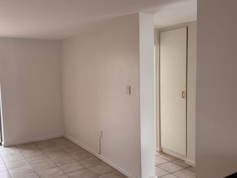 A clean, empty hallway featuring neutral tiled flooring and a built-in storage cupboard, providing a functional transition space within the apartment.