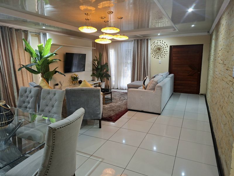 Spacious open-plan living and dining area featuring glossy ceilings, tiled floors, and a striking stone feature wall, creating a modern and inviting atmosphere.