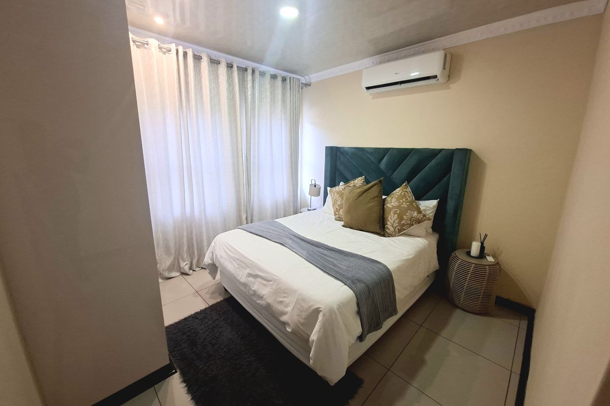 A well-maintained bedroom featuring tiled flooring, crown molding, recessed lighting, and a wall-mounted air conditioning unit.