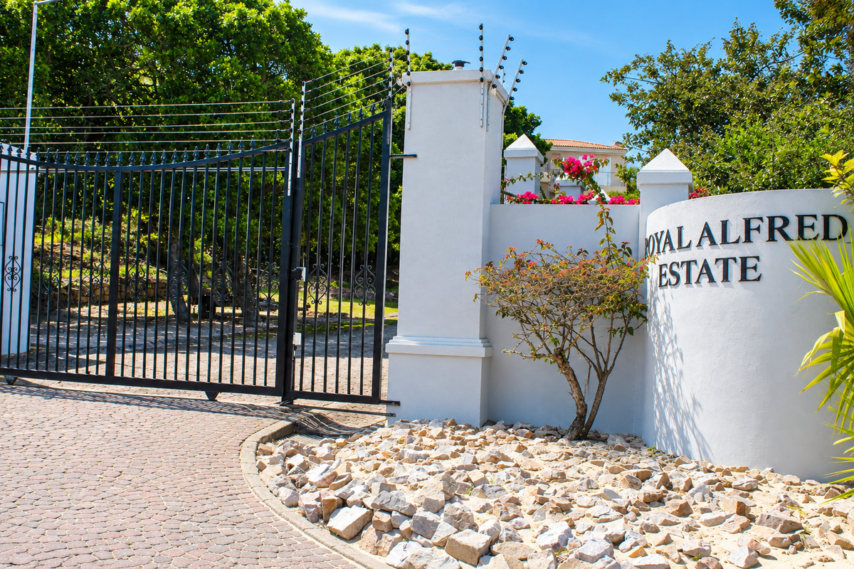 The entrance to Royal Alfred Estate featuring a secure wrought iron gate, electric fencing, and a well-maintained paved driveway.
