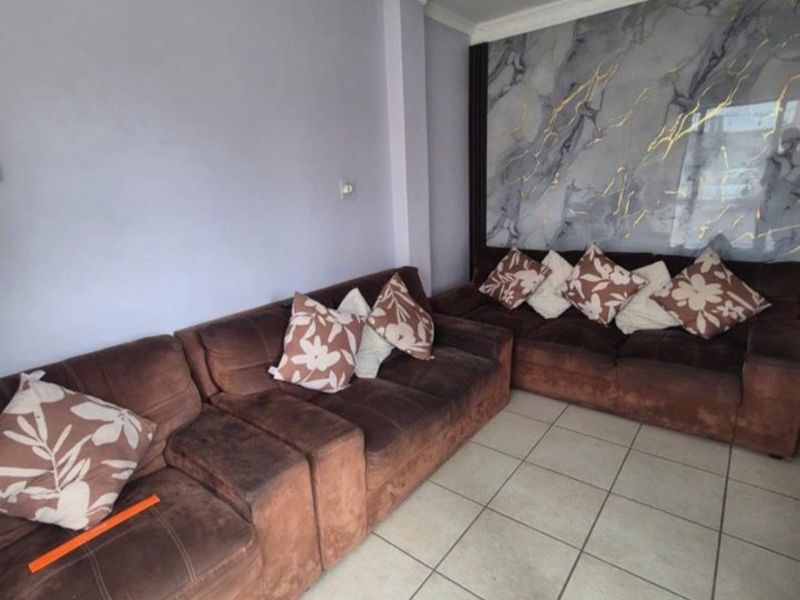 A living room featuring tiled flooring and a decorative marble-effect feature wall panel, providing a neutral base for potential interior updates.