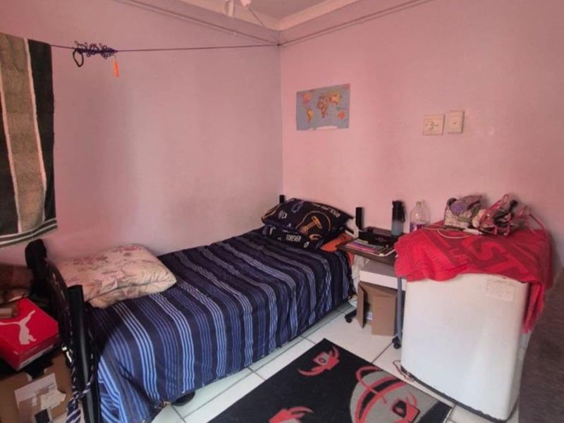 A compact bedroom featuring tiled flooring and standard electrical fixtures, requiring cosmetic updates to improve the overall aesthetic and finish.